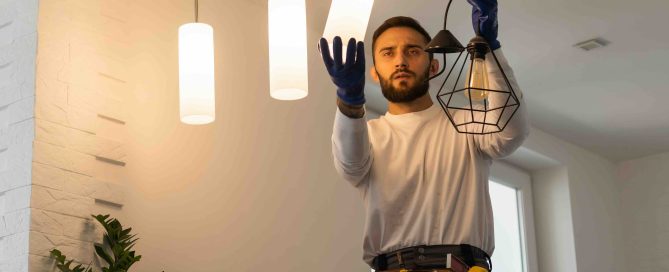 Picture of an electrician installing lighting fixtures in a house.