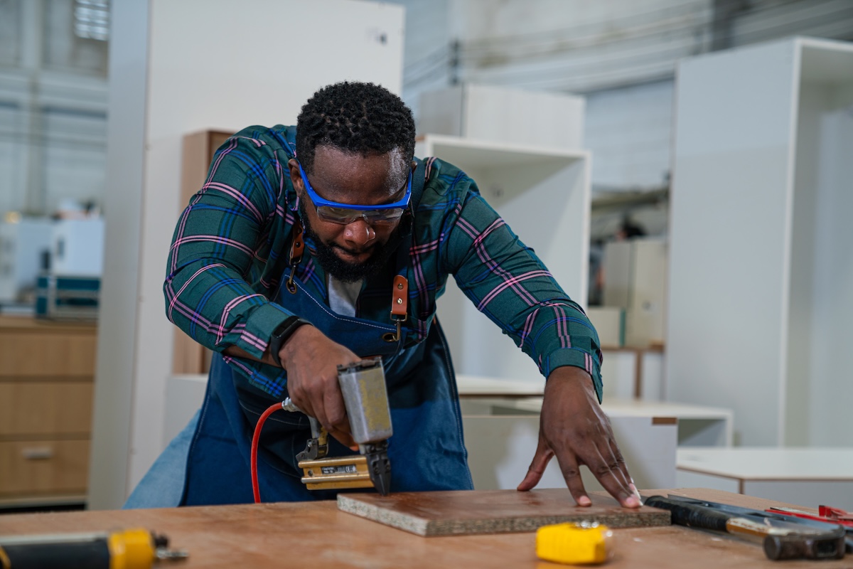 Afro american craftsman working as carpenter in a carpentry workshop.